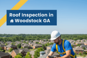 A professional roof inspector in a white hard hat and blue shirt is on a residential shingle roof, crouching to examine a damaged shingle while holding a tablet. A yellow inspection tool lies nearby, and a sprawling suburban neighborhood of Woodstock, GA, is visible in the background under a clear blue sky. The image features a badge blue and canary yellow overlay with a house icon and the title "Roof Inspection in Woodstock GA" in white text.